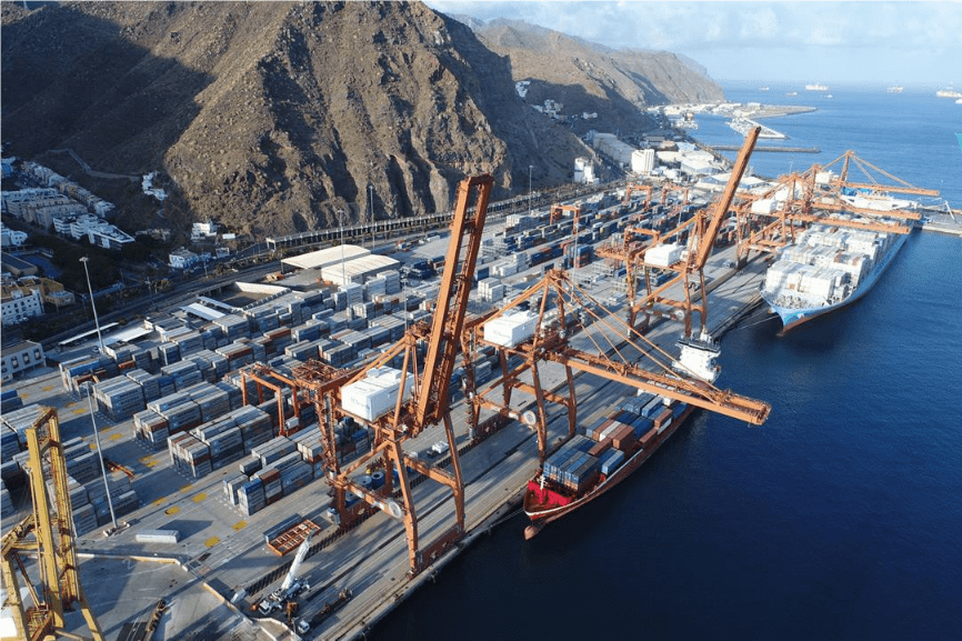 muelle con contenedores, montaña y mar