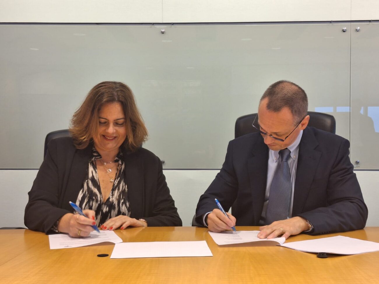 dos personas sentadas firmando un papel